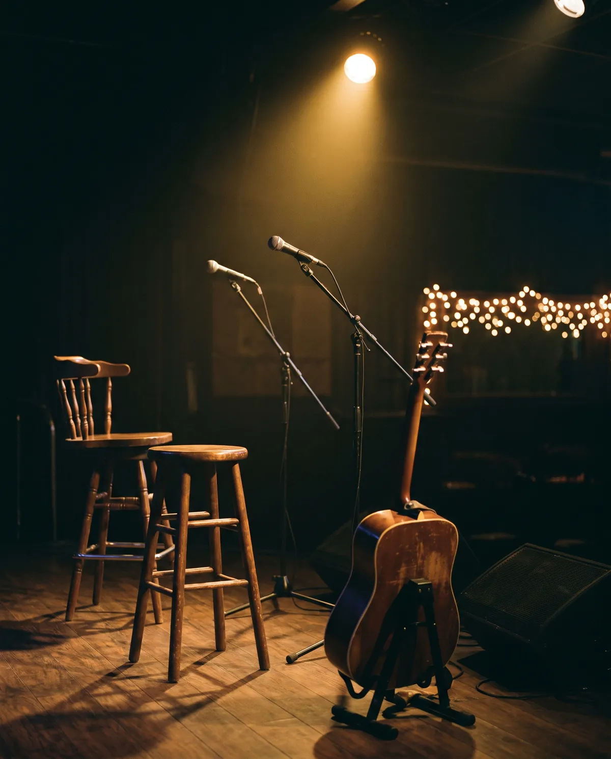 Kleine Bühne mit Akustikgitarre, zwei Mikrofonen und zwei Hockern